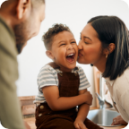 A mother kisses her son on the cheek. 